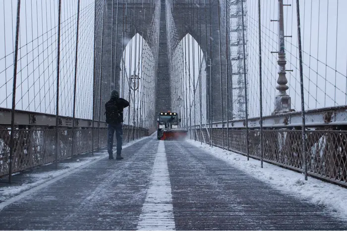Snow and a snowplow on the Brooklyn Bridge pedestrian path.